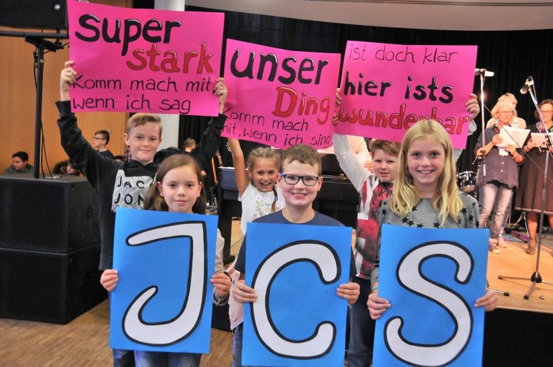 Bild: Kinder halten Plakate mit den Buchstaben JCS